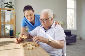 Caregiver helping a senior with dementia put together a puzzle